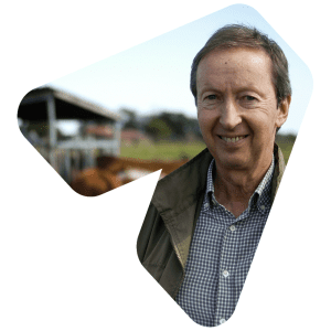 A dairy farmer smiling into the camera with cows in the background