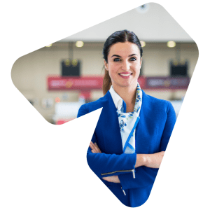 An airline employee smiles into the camera with airport departure gates behind her