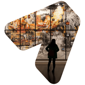 The silhouette of a woman can be seen from behind as she examines a wall of paintings in an art gallery